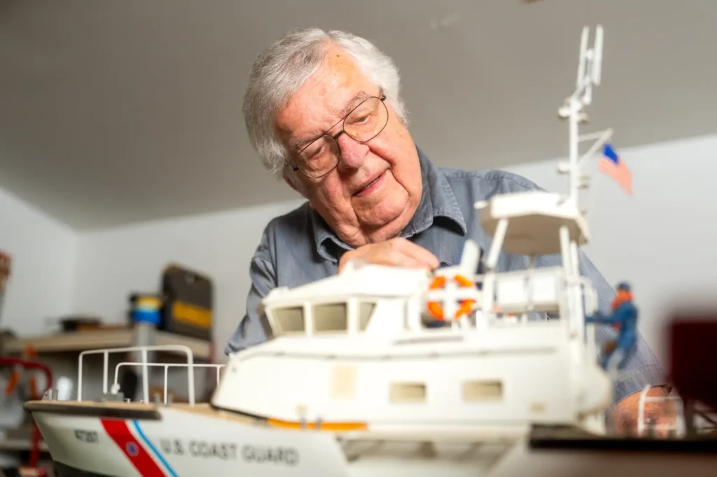A senior man working on painting a small boat collectible to hobby at Sandhill Cove, a retirement community in Palm City, FL