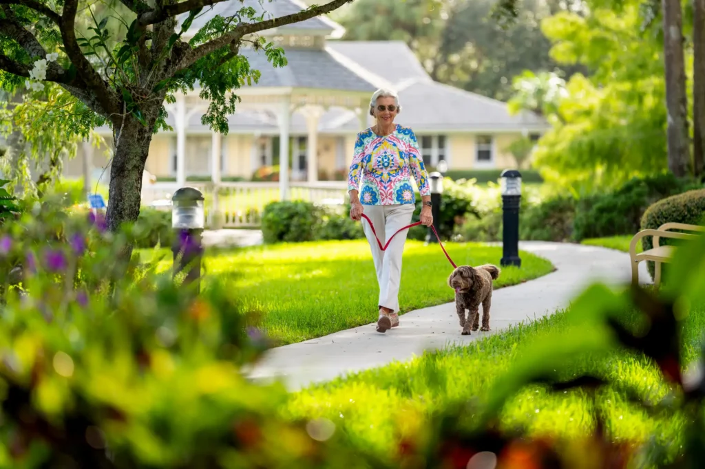 A senior woman walking her dog on the residences of Sandhill Cove, a retirement community in Palm City, FL.