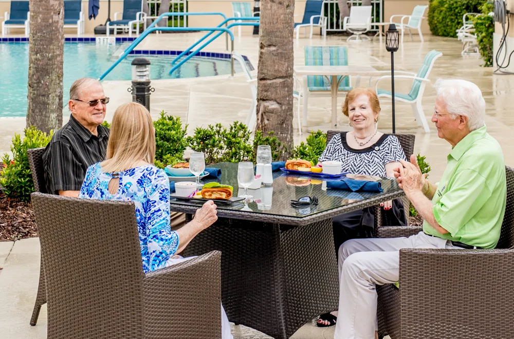 A group of seniors sit outside and enjoy a meal at their retirement home 