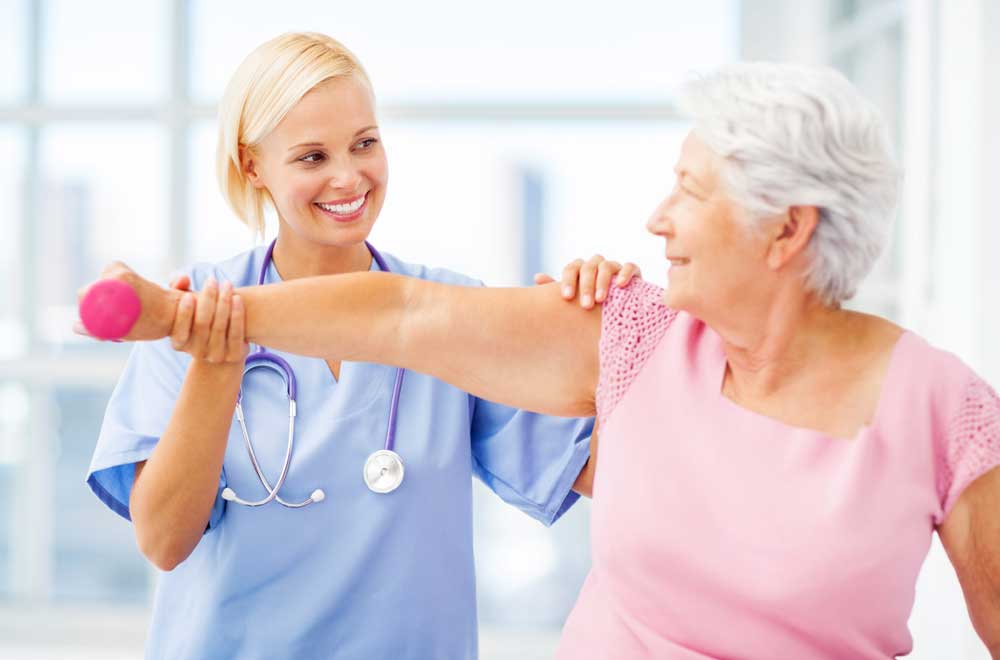 A senior woman doing hand weight exercises with a physical therapist 
