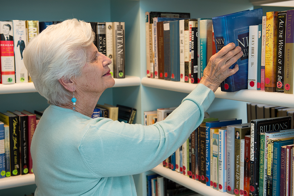 Senior resident looking through books in the library 